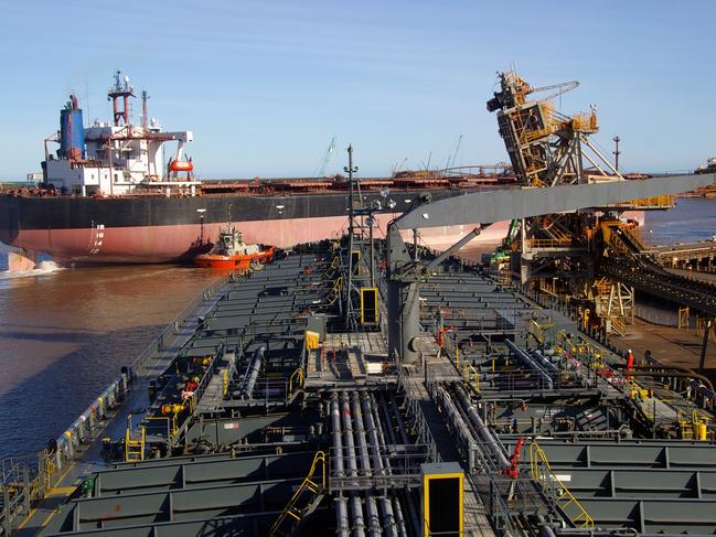 Industrial port in Western Australia, Port Hedland, view across petroleum product tanker deck to a Capesize bulk carrier approaching iron ore loading terminal, tug boats assisting. Picture: istock