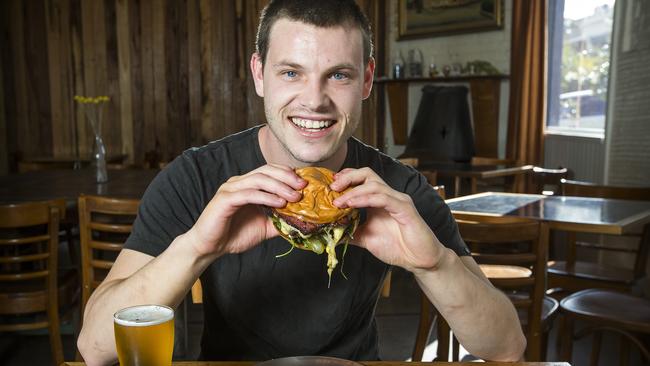 Hamburgers are taking over from the parma as the favorite pub grub. Mathew Zolli digging into a hamburger at Tramway Hotel in Fitzroy North. Picture: Sarah Matray