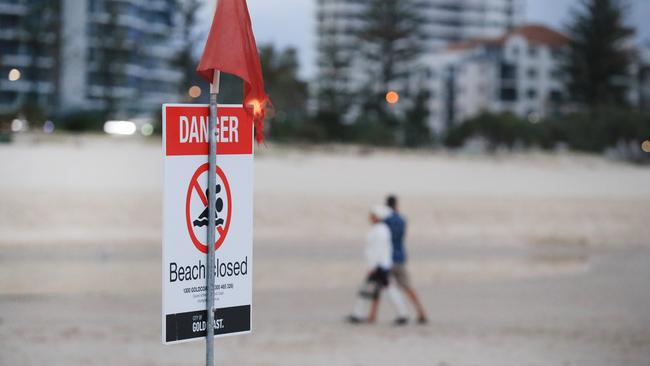 People walking by a beach closed sign this morning. Photo: Scott Powick.