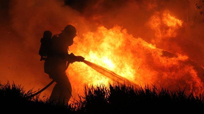 A firefighter works to put out a vegetation fire.