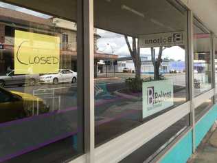 Pieces of yellow paper with the words "closed" hang in the windows of Boltons Furniture in Ellena St, Maryborough.