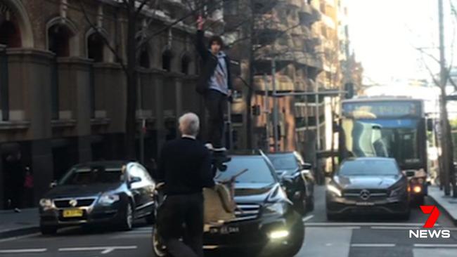 John Bamford, aka chair man, approaches Mert Ney as he stands on the bonnet of a car with a butcher’s knife in Sydney’s CBD. Picture: Seven News