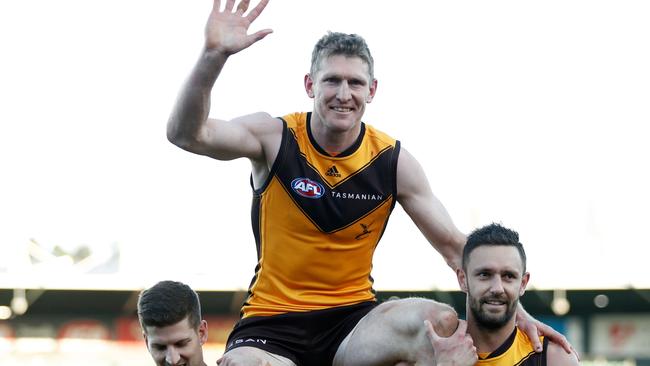 LAUNCESTON, AUSTRALIA - AUGUST 06: Ben McEvoy of the Hawks is chaired off the ground by teammates Luke Breust of the Hawks (L) and Jack Gunston of the Hawks (R) during the 2022 AFL Round 21 match between the Hawthorn Hawks and the Gold Coast Suns at UTAS Stadium on August 6, 2022 in Launceston, Australia. (Photo by Dylan Burns/AFL Photos via Getty Images)