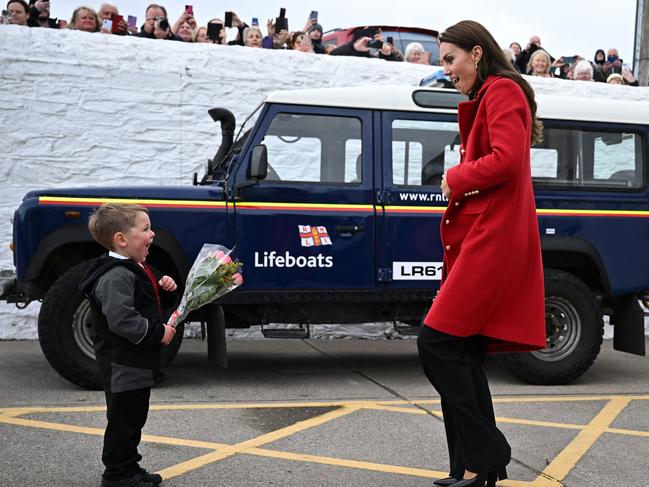 Britain's Prince William, Prince of Wales (R) watches as his wife Britain's Catherine, Princess of Wales is presented with a posy of flowers by four-year-old Theo Crompton during their visit to the RNLI (Royal National Lifeboat Institution) Holyhead Lifeboat Station in Anglesey, north west Wales on September 27, 2022. (Photo by Paul ELLIS / POOL / AFP)