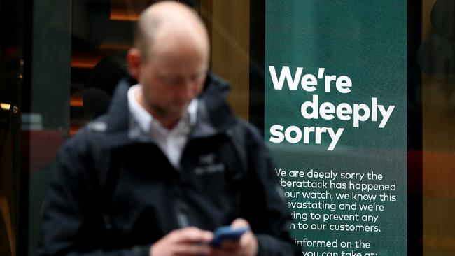 A person uses their phone while an Optus public service message is displayed inside an Optus store in Sydney. Picture: Brendon Thorne/Getty Images