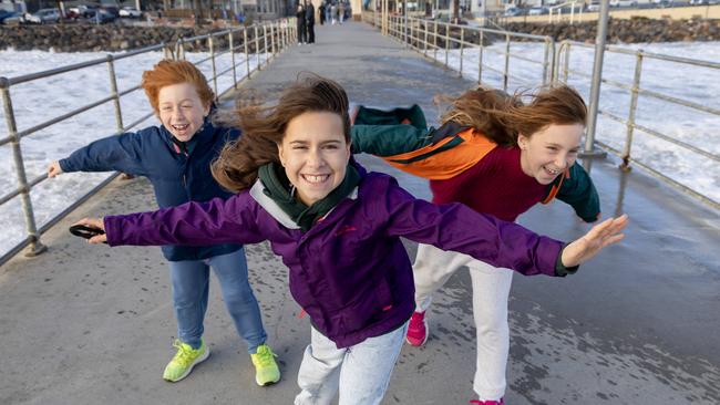 Siblings George 8 , Isabella 10, and Olivia 10 getting blown away on Brighton Jetty. Picture by Kelly Barnes