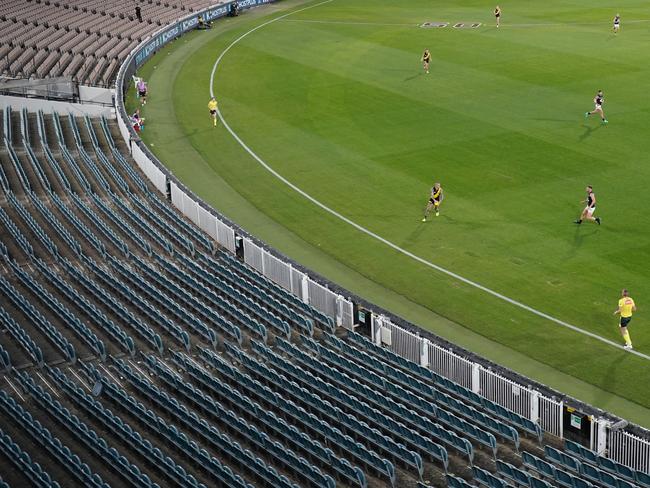 Dustin Martin of the Tigers runs with the ball while the MCG sits empty. Picture: Getty Images