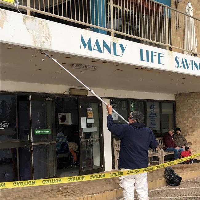 A painter preparing the outside of the Manly Life Saving Club for a coat of paint in August, 2022. Picture: Jim O'Rourke