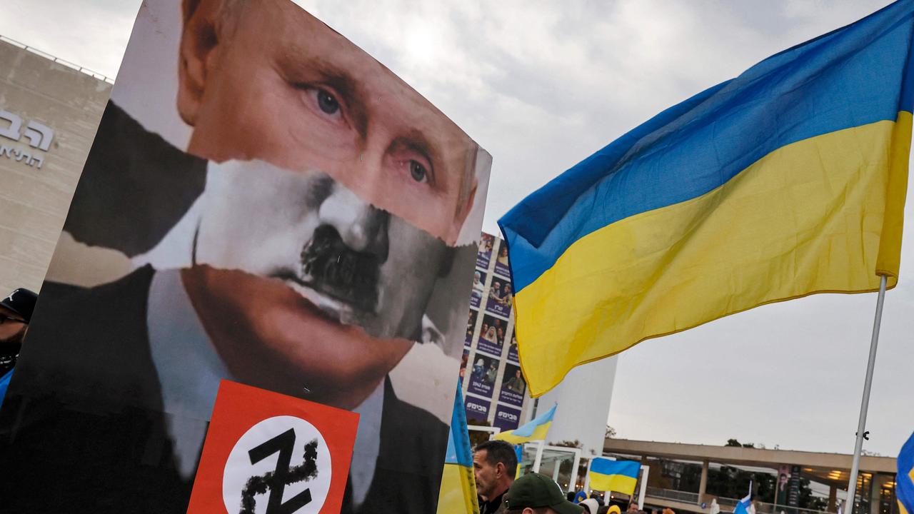 A demonstrator holds up a sign depicting the superimposed face of Russian president Vladimir Putin atop the signature moustache of Nazi Germany's leader Adolf Hitler. Picture: Jack Guez/AFP