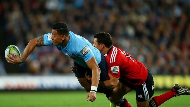 Israel Folau gets an offload away despite a tackle from Crusaders star Dan Carter.