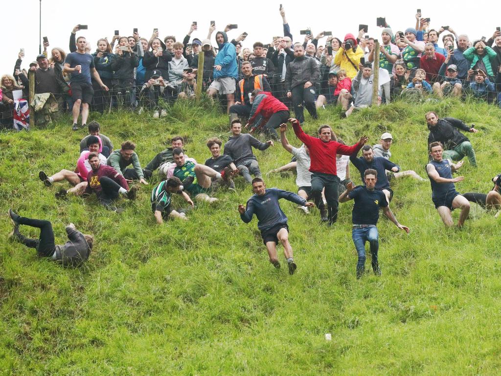 GLOUCESTER, ENGLAND - JUNE 05: Contestants in the men's downhill race chase the cheese down the hill on June 05, 2022 in Gloucester, England. The Cooper's Hill Cheese-Rolling and Wake annual event returns this year after a break during the Covid pandemic. It is held on the Spring Bank Holiday at Cooper's Hill, near Gloucester and this year it happens to coincide with the Queen's Platinum Jubilee. Participants race down the 200-yard-long hill after a 3.6kg round of Double Gloucester cheese. (Photo by Cameron Smith/Getty Images)