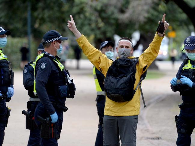 Police speak to a demonstrator at the anti-lockdown protest near the Shrine of Remembrance. Picture: Andrew Henshaw