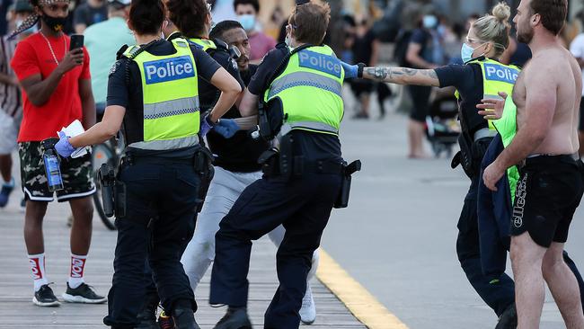 A man is arrested along St Kilda foreshore apparently drunk while not wearing a mask Picture: Ian Currie