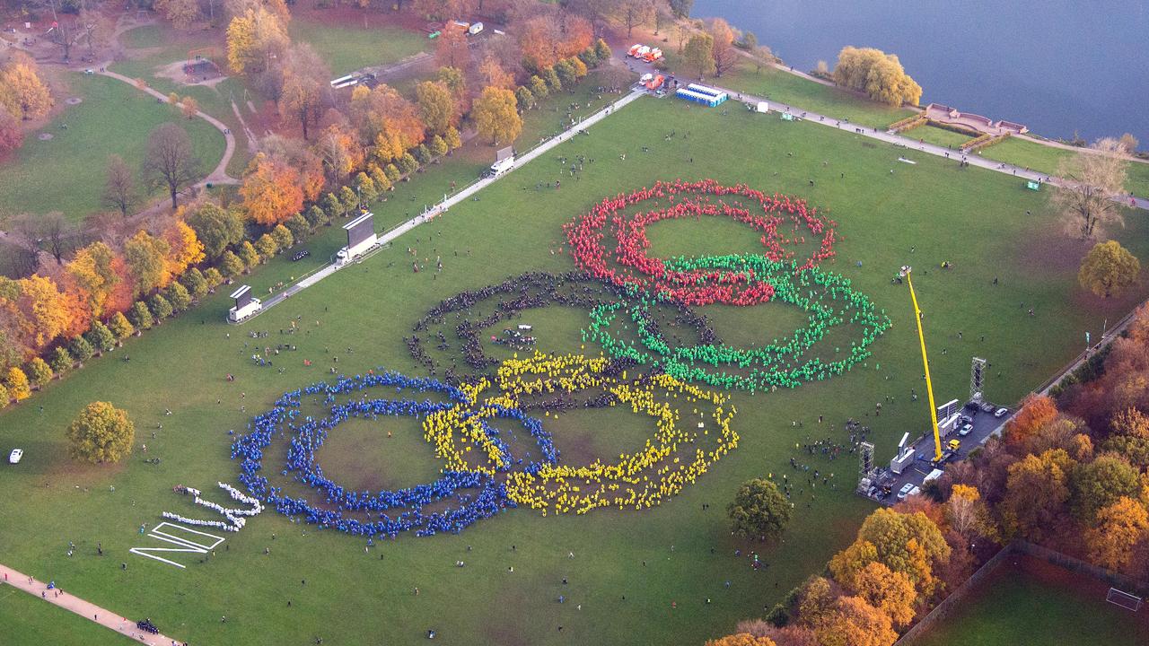 An aerial view shows thousands of people wearing colorful ponchos to form the Olympic rings to support Hamburg's bid for the Olympics 2024, in a park in Hamburg, Germany, Sunday Nov. 8, 2015. At left, protesters against Hamburg's Olympic bid laid the word "NO" next to the giant Olympic logo, but backers formed the letter W to turn the word into “NOW.” (Daniel Bockwoldt/dpa via AP)