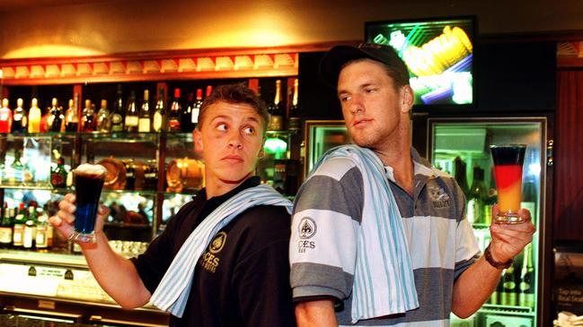 Footballers Michael Wilson and Brent Williams holding cocktails of their teams’ respective colours at Aces.