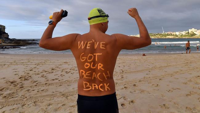 A man poses with a message on his back before enjoying his first swim after Bondi Beach reopened following a five week closure in Sydney on April 28, 2020, amid the novel coronavirus pandemic. - Swimmers and surfers returned to Sydney's famed Bondi Beach almost six weeks after it was closed amid a spike in coronavirus cases. (Photo by Saeed KHAN / AFP)