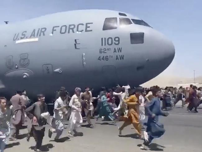 People run on tarmac of Kabul international airport as a US military aircraft attempts to take off.