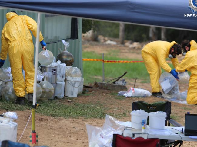 Police wearing protective suits and breathing masks sort through the stockpile of tubs removed from the shed. Picture: Police Media.