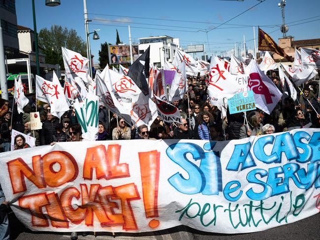 Protestors hold a banner reading "No to ticket, Yes to houses and services for all" as they take part in a demonstration, against the new "Venice Access Fee", organised by the list "Tutta la cittaâ insieme" (The whole city together) and members of several Venetians trade associations in "Piazzale Roma" in Venice, on April 25, 2024. Venice launched a new scheme to charge day-trippers for entering the historic Italian city, a world first intended to ease the pressure of mass tourism , but many residents are opposed, in Venice, on April 25, 2024. (Photo by MARCO BERTORELLO / AFP)