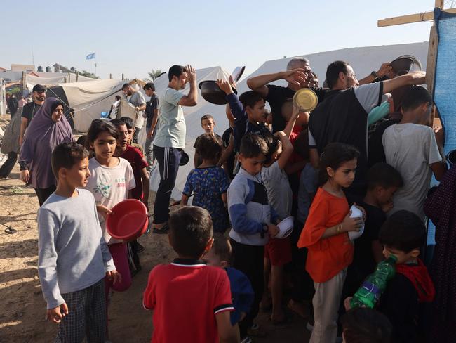 Displaced Palestinians, who fled their houses amid Israeli strikes, wait for food at a United Nations-run centre. Picture: AFP