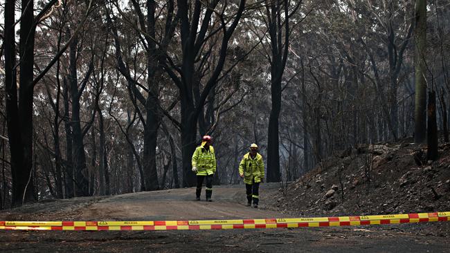 Two rural firefighters walk along Skyline Rd at Mount Tomah on Monday. Picture: Adam Yip