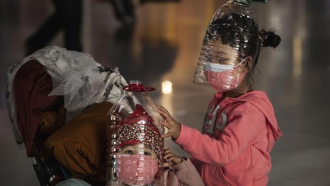 Chinese children wear plastic bottles as makeshift homemade protection and protective masks at Beijing Airport.