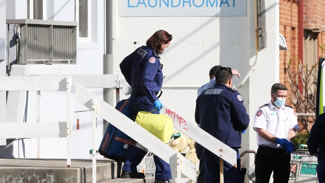 Paramedics leave the unit block after being unable to save Mr Prentice. Picture: Peter Lorimer