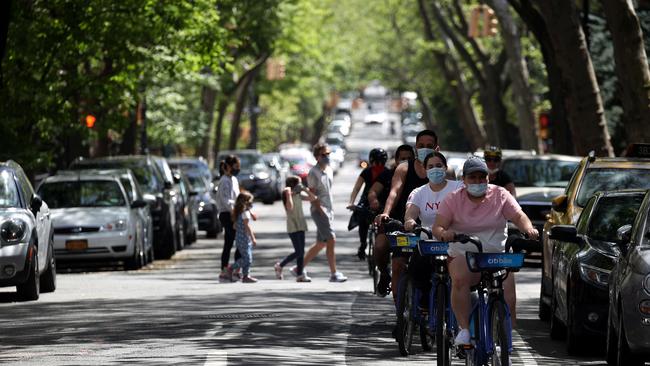 Bicyclists wearing protective face masks ride down a street during the coronavirus pandemic of 2020. Picture: Justin Heiman