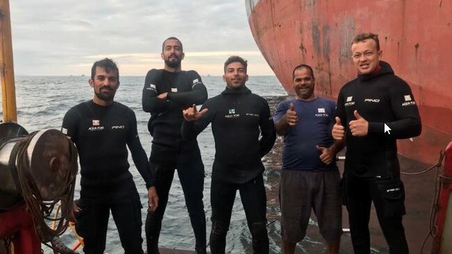 Bruno Borges (centre) with fellow divers near a ship. Picture: Supplied