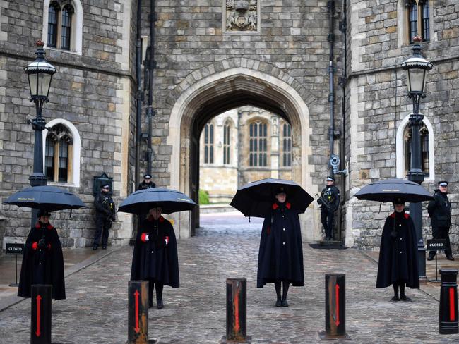 Wardens of the Castle shelter from the rain beneath umbrellas outside Windsor Castle where Prince Philip’s body is currently lying in the castle’s chapel. Picture: AFP