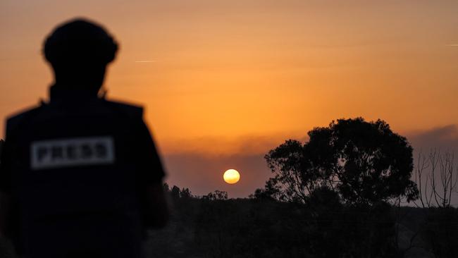 A journalist looks on as the sun sets over the Gaza Strip off a position across the border in southern Israel.