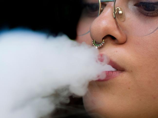 A woman blows smoke from an electronic cigarette in San Jose on May 14, 2024. Costa Rican authorities announced Tuesday that they will "ban products containing synthetic nicotine" in the country, targeting the substance used in packaging for smoking in vapes and electronic cigarettes. (Photo by Ezequiel BECERRA / AFP)