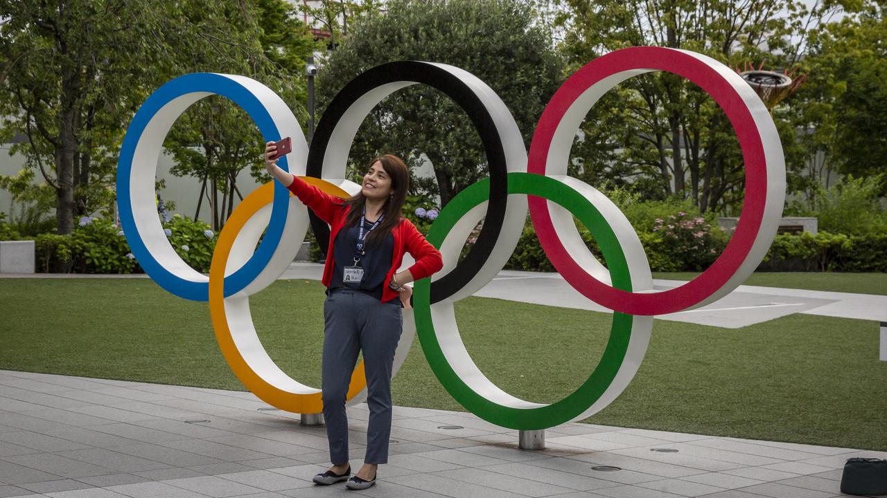 A woman takes a selfie in front of the Olympic Rings in Tokyo. (Photo by Yuichi Yamazaki/Getty Images)