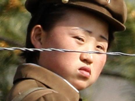 08/06/2009 WIRE: In this photo taken June 3, 2009, a female North Korean soldier looks out from behind a barbed-wire fence around a camp on the North Korean river banks across from Hekou, northeastern China's Liaoning province. North Korea's top court has convicted two U.S. journalists, and sentenced them to 12 years in labor prison, the country's state news agency reported Monday. (AP Photo/Ng Han Guan)