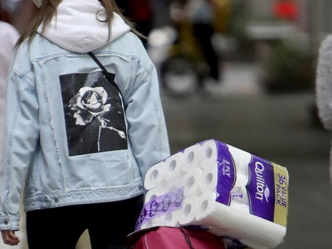 25/03/2020: A woman wearing a mask takes home her shopping including toilet paper & mop. Only a small number of people remain on the streets of Melbourne as a social exclusion period comes in to affect, to try and slow the spread of Coronavirus in Australia. Stuart McEvoy/The Australian.