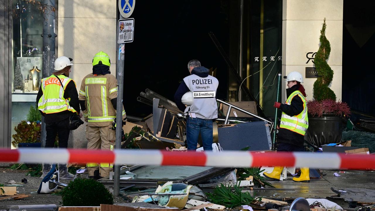 Policemen and firefighters stand among debris covering the street in front of the Radisson Blu hotel after a huge aquarium located in the hotel's lobby burst. (Photo by John MACDOUGALL / AFP)