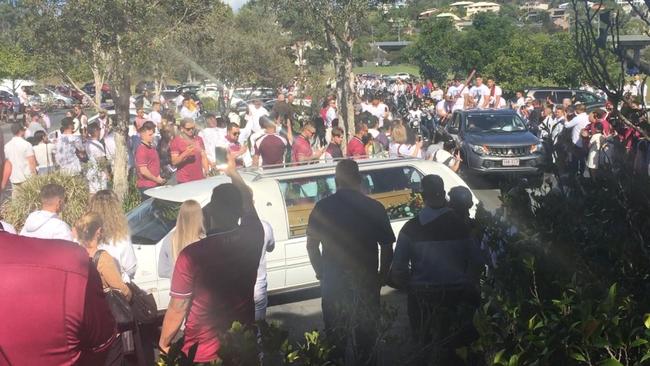 A large crowd of mourners watches as the hearse carrying much-loved player Navar Herbert arrives at Nerang Bulls Rugby Union club this morning.