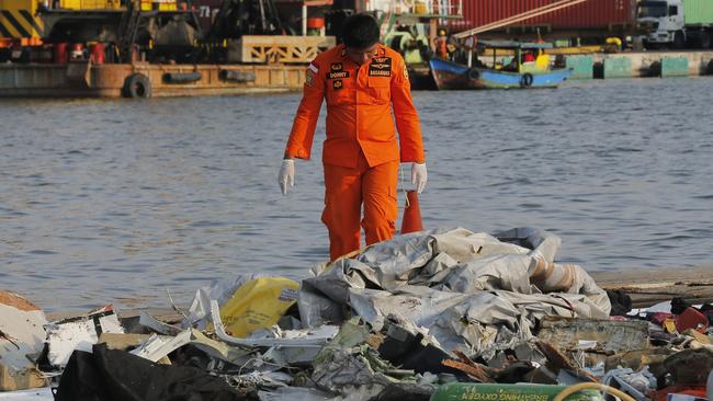 A member of the Indonesian Search and Rescue Agency (BASARNAS) inspects debris recovered from near waters where the plane is suspected to have crashed. Picture: AP.