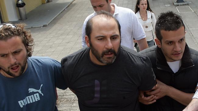 Tony Mokbel being escorted by Greek police, with McGuire's daughter Brittany in the background, after his arrest in Glyfada, Greece.