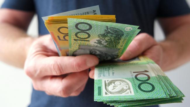 A man counting Australian dollar bills. A picture that describes buying, paying, handing out money, or showing money. Australian cash money generic