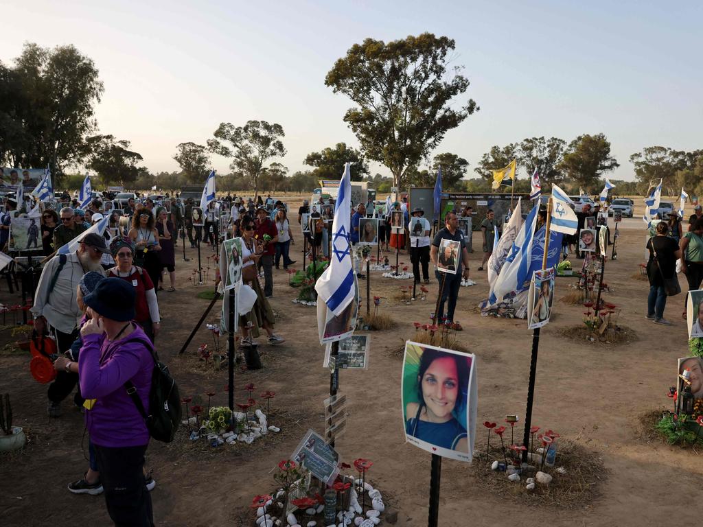 Visitors pay their respects at a memorial bearing portraits of people taken hostage or killed in the Hamas attack on the Supernova music festival on October 7. Picture: AFP