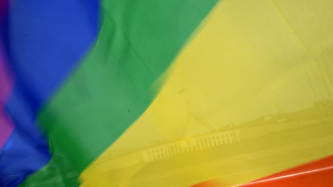 Parliament House is seen through a rainbow flag during a rally in support of same sex marriage outside Parliament House in Canberra, Tuesday, September 12, 2017. (AAP Image/Lukas Coch) NO ARCHIVING