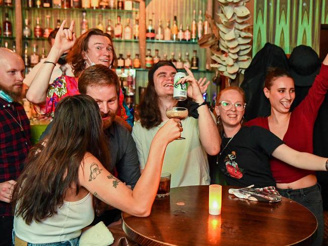 People celebrate in a bar in Melbourne on October 22, 2021, as one of the world's most locked-down cities reopened, with Melbourne residents hoping this sixth bout of stay-at-home restrictions will be their last. (Photo by William WEST / AFP)