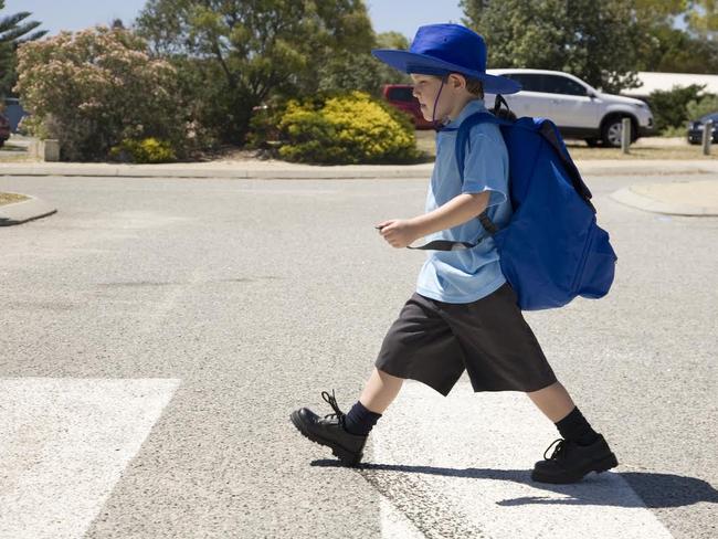 A five year old Australian school boy crossing the car park safely.