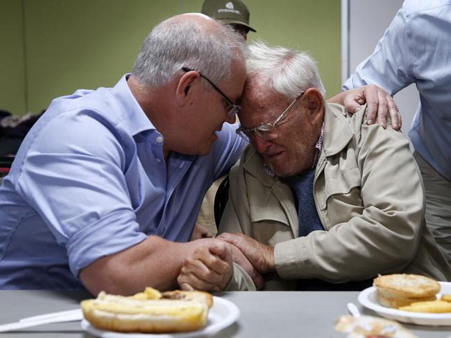 Prime Minister Scott Morrison is seen comforting 85 year old Owen Whalan of Half Chain road in Koorainghat who has been evacuated from his home during a visit to Club Taree Evacuation Centre in Taree, New South Wales, Sunday, November 10, 2019. (AAP Image/Darren Pateman) NO ARCHIVING