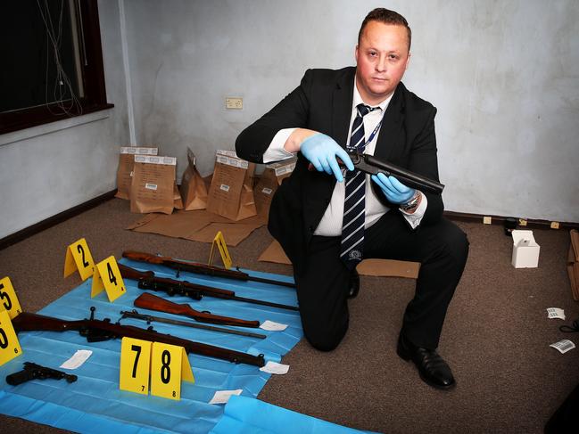 Detective Senior Constable Ryan Jeffcoat with eight guns and a stab proof vest where found under a house in Hollywood Drive at Lansvale in 2013.