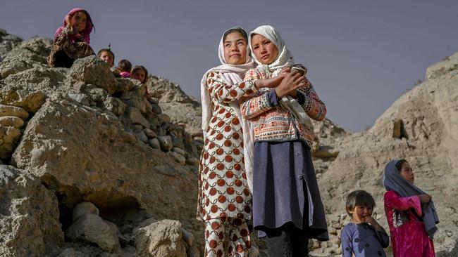 Hazara ethnic people stand on a cliff pockmarked by caves where people still live as they did centuries ago in Bamiyan, Afghanistan. Picture: AFP