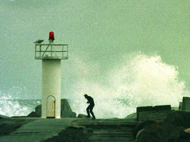 1999. A photographer dodging the spray from large waves at the southern wall of the Gold Coast Seaway.