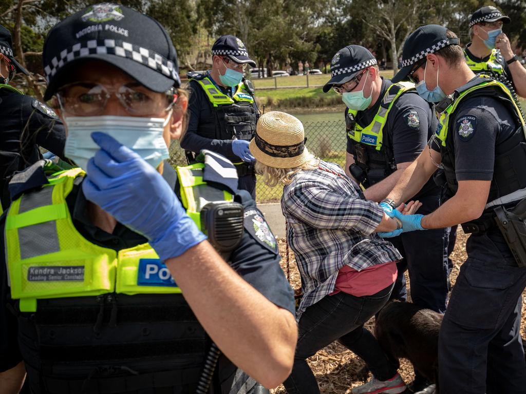 A woman is detained by police at Elsternwick Park on Saturday. Picture: Darrian Traynor/Getty Images