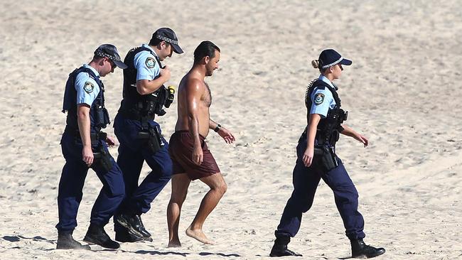 Police are seen removing a man from Coogee Beach after the beach was closed because too many people were flouting COVID-19 rules. Picture: Matrix